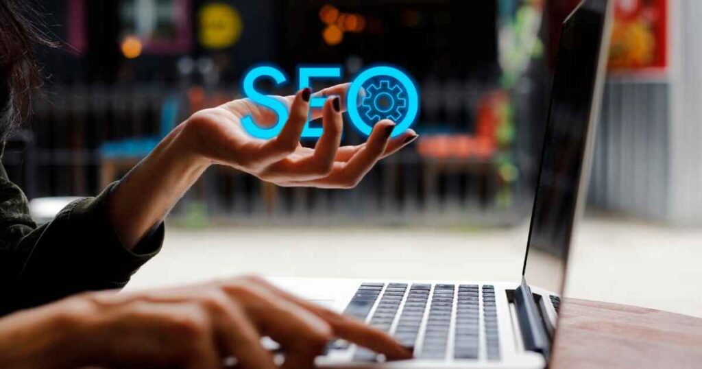 a person on a laptop typing and holding the words SEO in the other hand