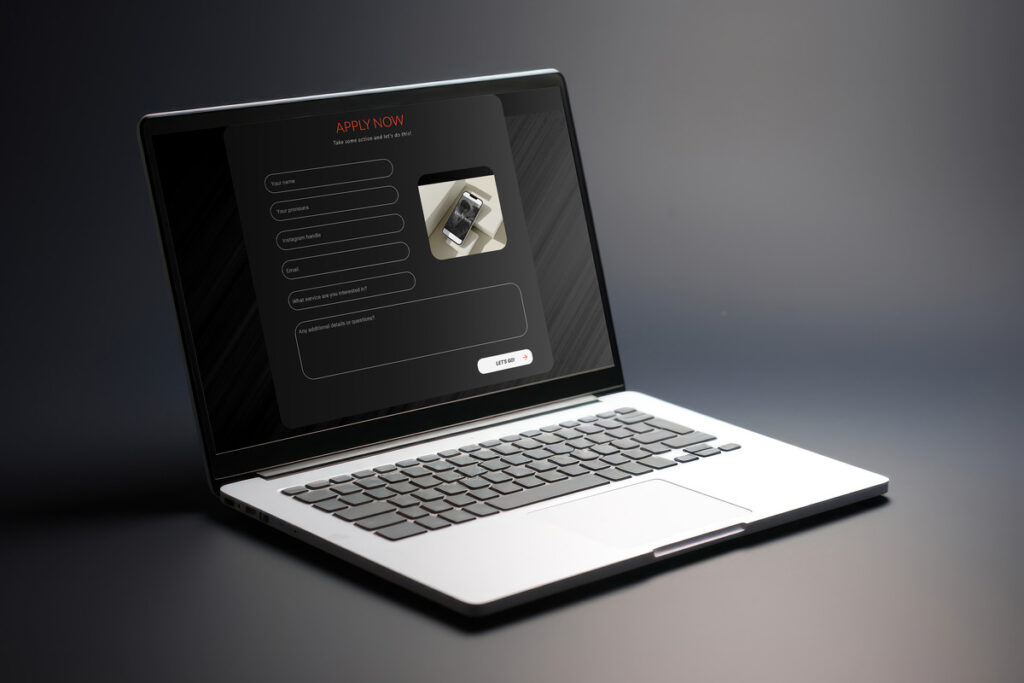 A laptop displaying a sleek, dark-themed contact form for a photography website. The form includes fields for name, pronouns, Instagram handle, email, service interest, and additional details. The page also features an image of a smartphone displaying a wedding photography website