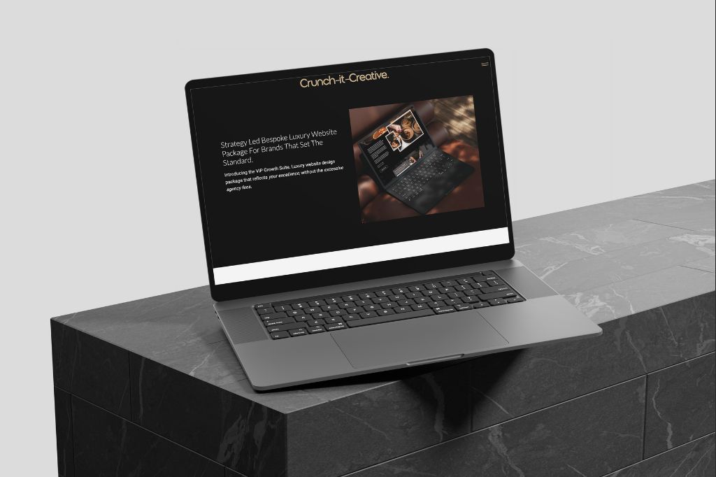 Angled laptop showing a luxury website redesign package page titled “Crunch-it-Creative” with a photo of a laptop and warm-toned visuals.